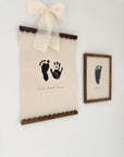 Decorative wall art with footprints and a bow on a white background