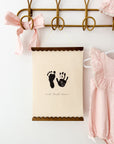 Decorative wall hanging with footprints and text on a white background