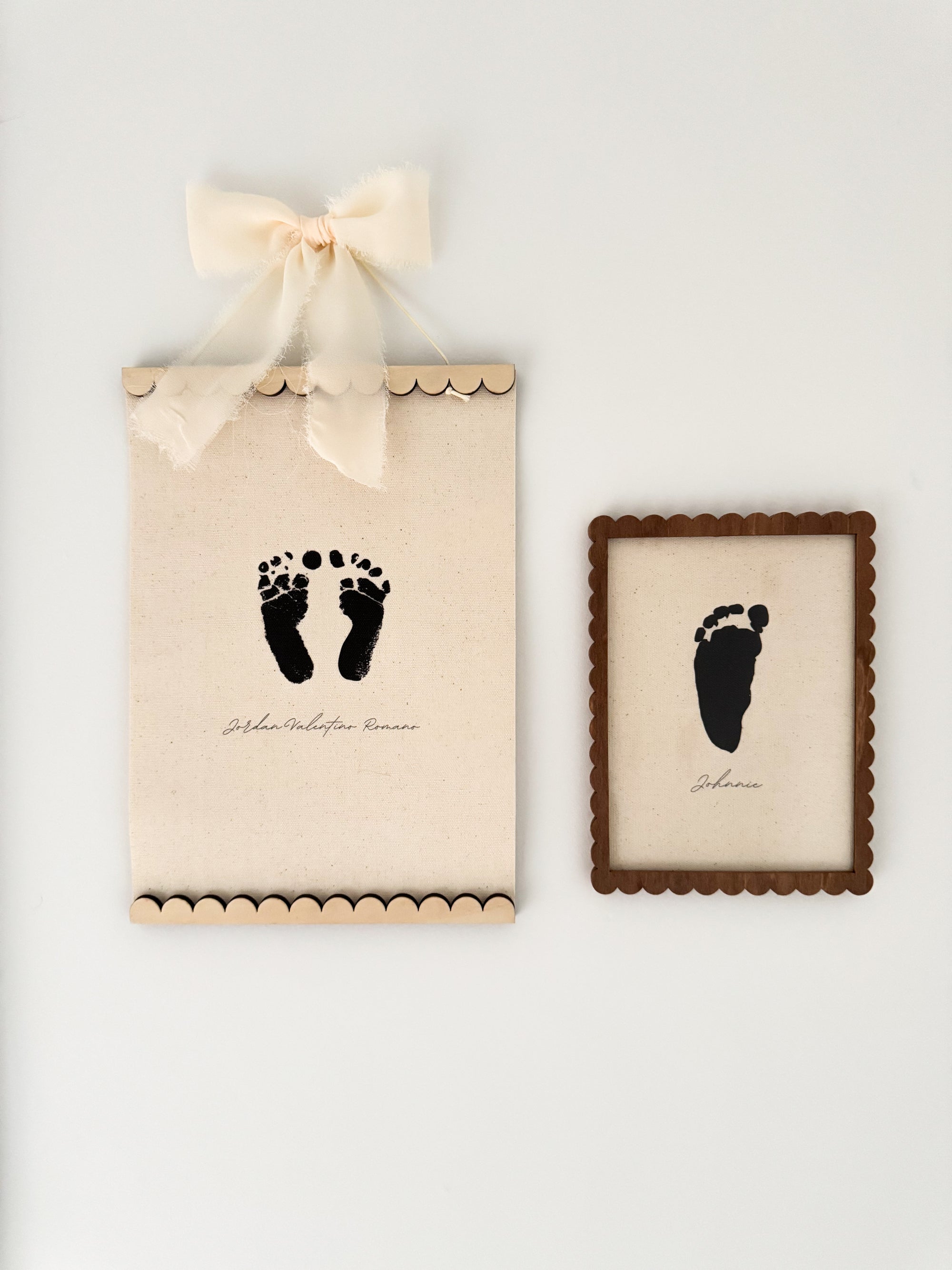 Framed black footprints on a beige background with a decorative bow.